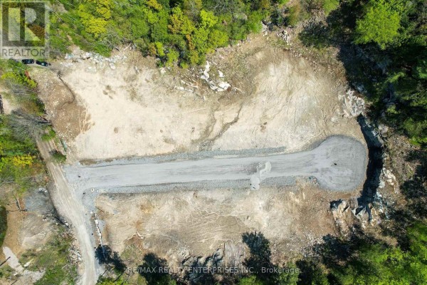 Overhead drone shot of the undeveloped land, featuring a newly constructed gravel driveway with a cul-de-sac. - 120 Townline Road E, Huntsville