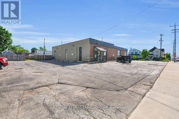 Rear view of the commercial building showing the parking lot and surrounding houses. - 120 Vidal Street N, Sarnia