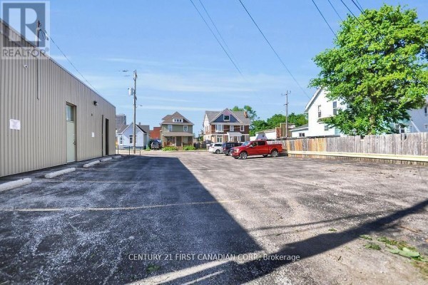 Parking lot behind the commercial building with residential homes visible in the background. - 120 Vidal Street N, Sarnia