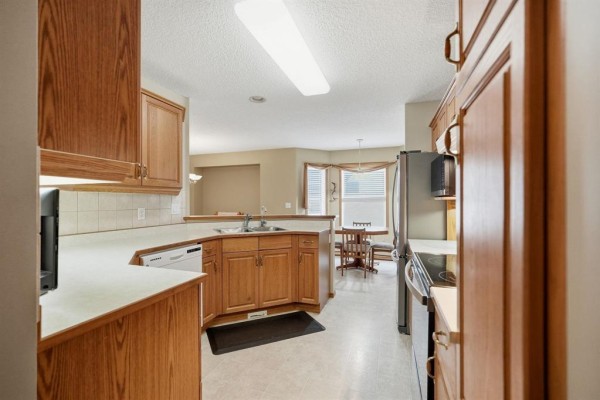 View from the kitchen into a dining area with a round wooden table and chairs. - 120 Wyndstone Circle, East St Paul