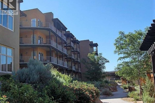 Terraced stucco building with balconies and metal railings under a clear blue sky. - 1200 Rancher Creek Road Unit# 115d, Osoyoos