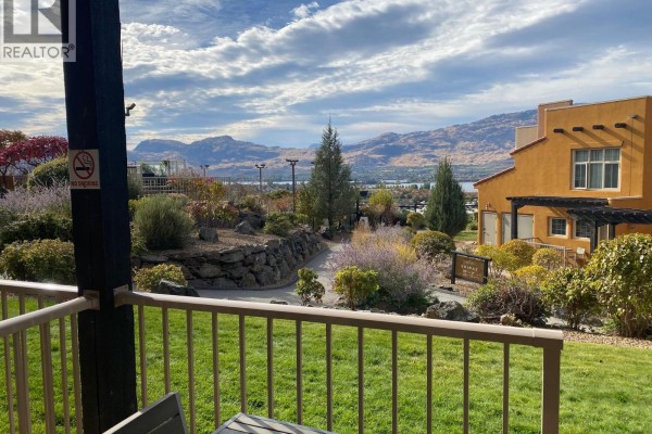 View from balcony with green grass, landscaping, mountains, and lake in the distance. - 1200 Rancher Creek Road Unit# 115d, Osoyoos