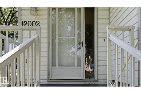 Close-up of the front door with a screen door and white railings. - 12002 91 St Nw, Edmonton