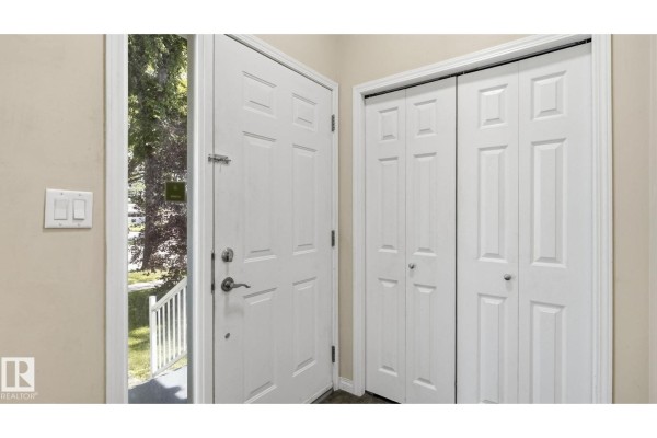 Interior view of the front entrance with a white door and double closet doors. - 12002 91 St Nw, Edmonton