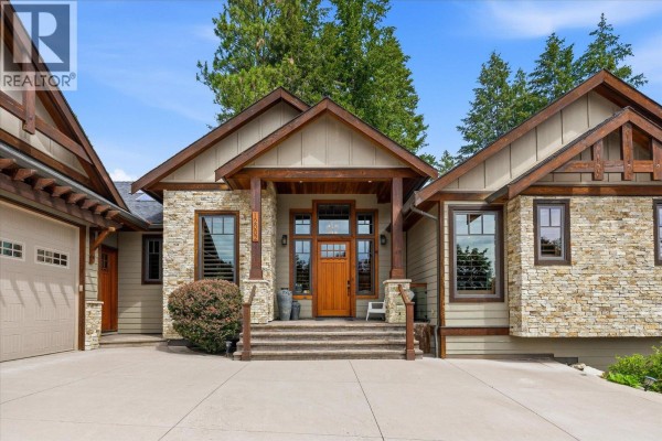 Close-up of the wood front door, stone exterior, and entryway stairs with wood railings. - 12002 Middleton Road, Lake Country