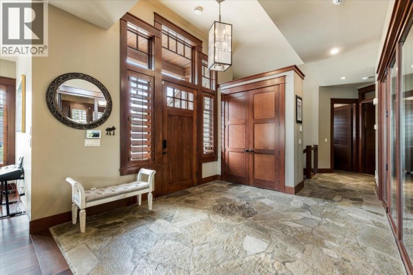 Spacious foyer with a flagstone floor, dark wood trim, and a white upholstered bench. - 12002 Middleton Road, Lake Country