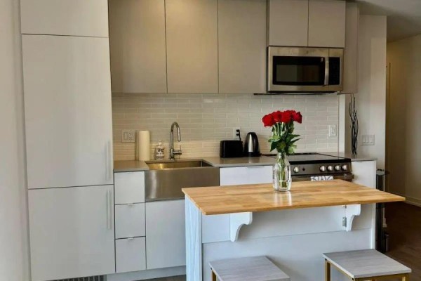 Compact kitchen with white cabinets, stainless steel appliances, and a butcher block island. - 1201 - 270 Dufferin Street, Toronto