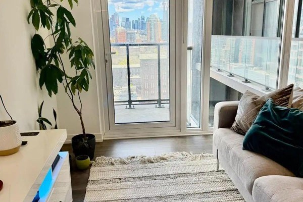View of the living room balcony through glass doors with the Toronto skyline in the distance. - 1201 - 270 Dufferin Street, Toronto