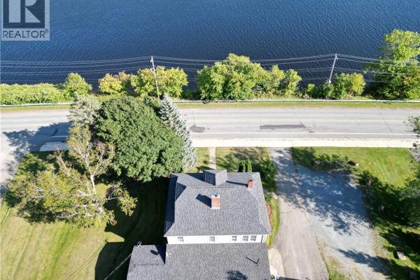 Aerial view of the property near a river, showing surrounding trees and road. - 1201 West Riverside Drive, Perth Andover