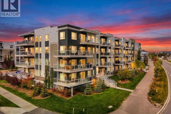 Exterior view of the apartment building at sunset with balconies and modern architecture. - 1202, 220 Seton Grove Se, Calgary