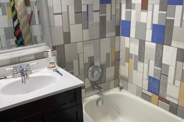 Bathroom with a white bathtub, sink, and wall tiles in a geometric pattern. - 1202 - 100 Lotherton Pathway, Toronto