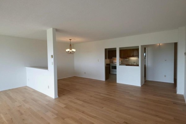 Living room with carpet, furniture, large window with view, and wooden cabinet. - 1202 - 1000 King Street W, Kingston