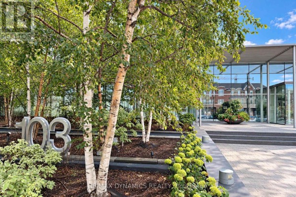Exterior walkway with birch trees, plants, and metal "103" sculpture. - 1202 - 103 The Queens Way, Toronto