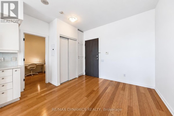 Apartment entryway with hardwood floors, white closet doors, and a doorway to a home office. - 1202 - 103 The Queens Way, Toronto