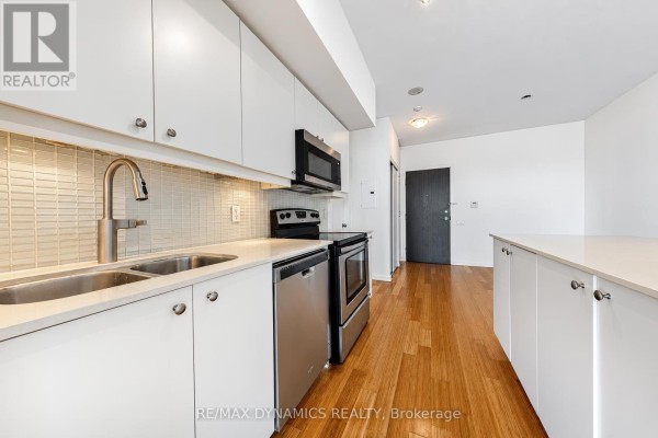 White galley kitchen with stainless steel appliances, quartz countertops, and a subway tile backsplash. - 1202 - 103 The Queens Way, Toronto