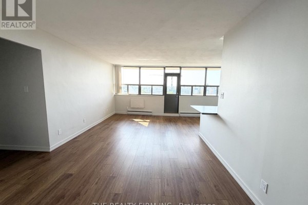Living area with hardwood floors, white walls, and a large window with a view. - 1202 - 1209 Richmond Street, London East