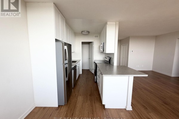 Open concept kitchen and living area with white cabinets and stainless steel appliances. - 1202 - 1209 Richmond Street, London East