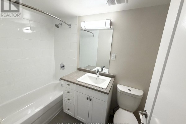 Bathroom with a white tub, vanity with sink, and toilet. - 1202 - 1209 Richmond Street, London East