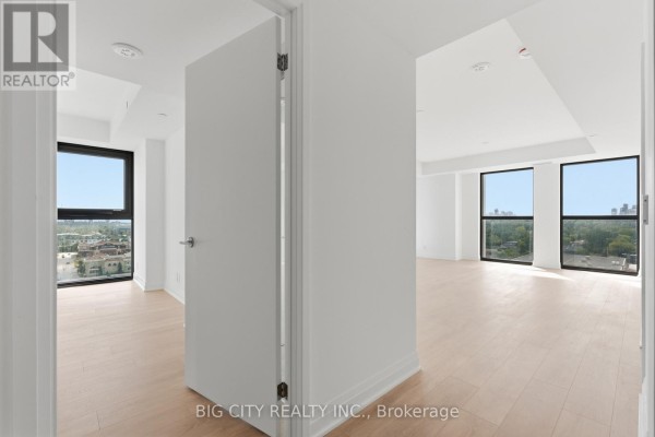 View from hallway into a bright living area with large windows and light wood floors. - 1202 - 25 Frederick Way, Toronto