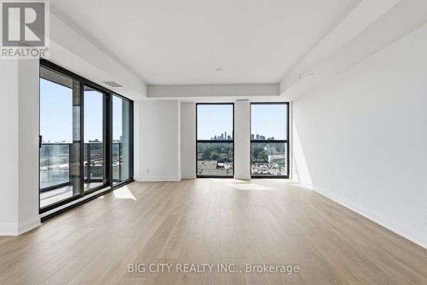 Living room with light wood floors and panoramic windows overlooking the city. - 1202 - 25 Frederick Way, Toronto