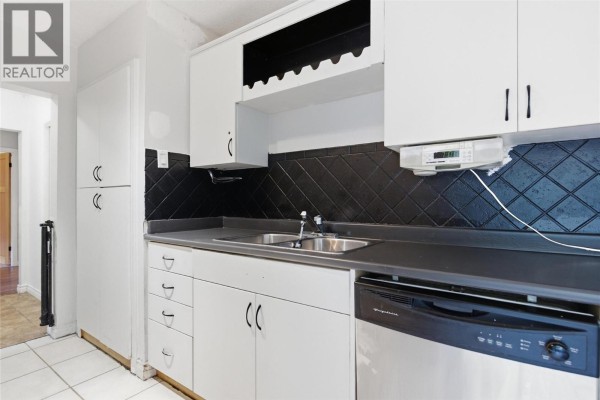 Kitchen with white cabinets, gray countertop, sink, and stainless steel dishwasher. - 1202 Crestwood Drive, Kamloops