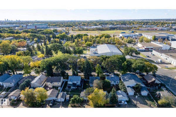Aerial view of a residential neighborhood with houses, trees, and commercial buildings in the background. - 12023 67 St Nw, Edmonton