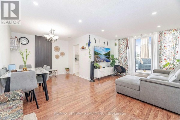 Living and dining area with wood floors, grey sofa, and marble table. - 1203 - 1615 Bloor Street, Mississauga