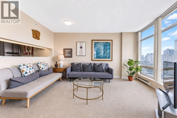 A living room with a television, coffee table, and city views, opening to a dining area. - 1203 1288 Alberni Street, Vancouver