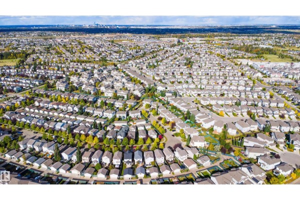 Wide aerial view of a dense suburban neighborhood with many two-story houses and trees. - 12035 18 Av Sw, Edmonton