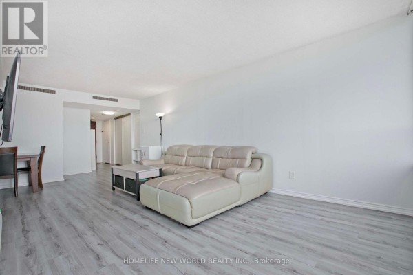 Living room with a sectional sofa, coffee table, dining set, and a hallway in the background. - 1204 - 160 Alton Towers Circle, Toronto
