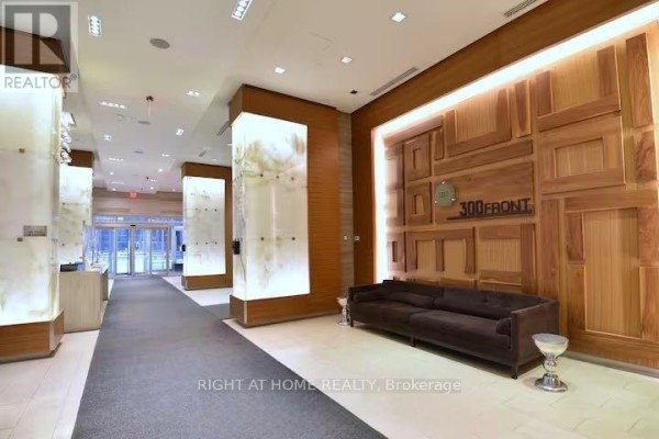 Building lobby with wood paneling, modern lighting, and a dark brown sofa. - 1204 - 300 Front Street W, Toronto