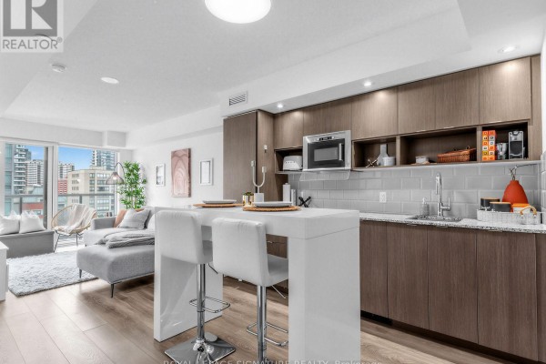 Open concept apartment living space with a kitchen island, seating, and sofa. - 1204 - 89 Mcgill Street, Toronto