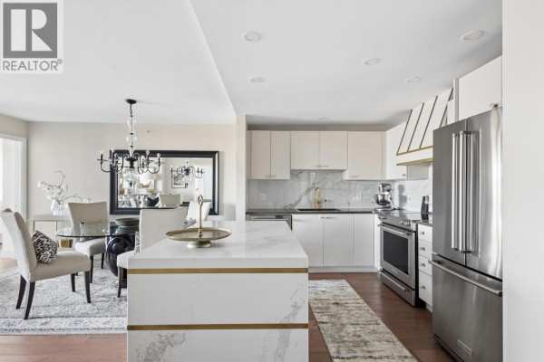 Modern kitchen with white cabinets, marble backsplash, island, and stainless steel appliances. - 1204 5611 Goring Street, Burnaby