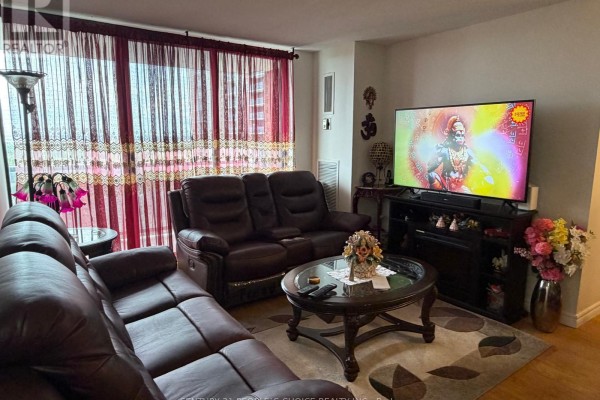 Living room with two brown leather sofas, coffee table, rug, and large TV on stand. - 1205 - 17 Knightsbridge Road, Brampton