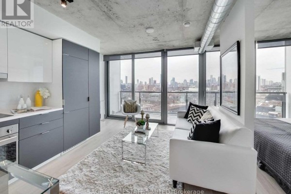 Living area with white sofa, grey kitchen cabinets, and large windows overlooking the city. - 1205 - 170 Bayview Avenue, Toronto