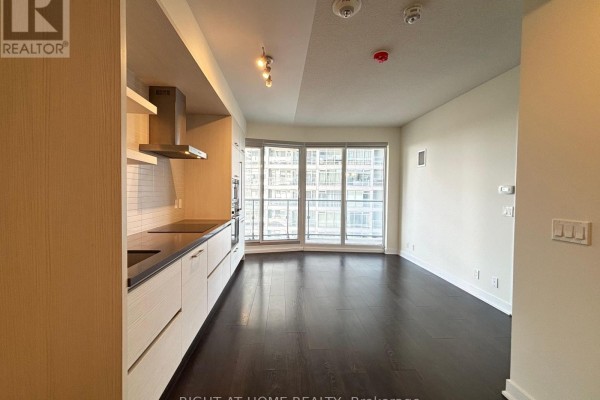 Modern kitchen with light wood cabinets, gray countertop, stainless steel appliances, and tile backsplash. - 1205 - 2221 Yonge Street, Toronto