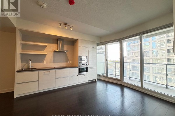 Corner of a kitchen with dark wood floors, grey blinds on window, and light wood cabinetry. - 1205 - 2221 Yonge Street, Toronto