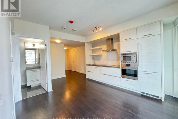 Kitchen view featuring light wood cabinets, stainless steel oven and microwave, and a grey countertop. - 1205 - 2221 Yonge Street, Toronto