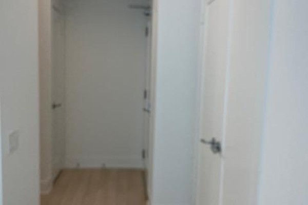 Hallway with white walls, closed doors, and a light wood floor. - 1205 - 310 Tweedsmuir Avenue, Toronto