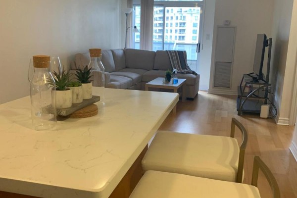 Kitchen island with decorative items overlooking a sectional sofa and coffee table in living room. - 1205 - 3880 Duke Of York Boulevard, Mississauga