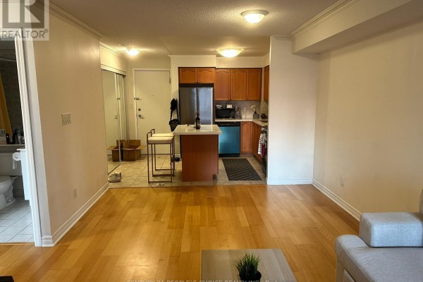 Open concept living area with hardwood floors, kitchen with wood cabinets, and entryway. - 1205 - 3880 Duke Of York Boulevard, Mississauga