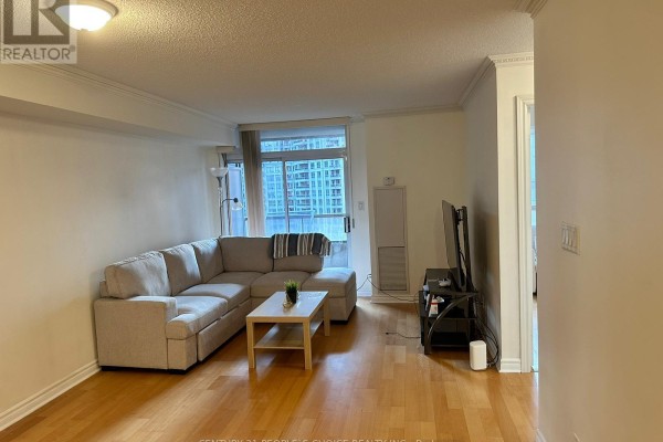 Living room with sectional sofa and coffee table looking towards the entryway. - 1205 - 3880 Duke Of York Boulevard, Mississauga