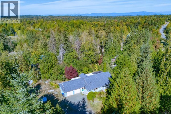 Aerial view of a house surrounded by dense evergreen forest. - 1205 Corcan Rd, Qualicum Beach