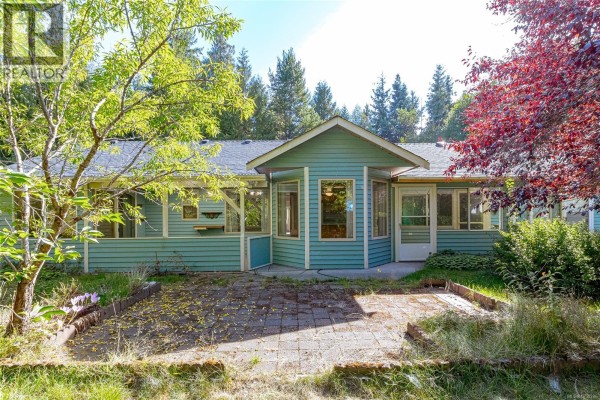 Back of the house featuring a sunroom and two paved patio areas. - 1205 Corcan Rd, Qualicum Beach