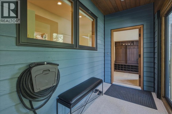 Exterior entry with blue siding, a bench, and a rolled-up hose. - 1205 Mount Fee Road, Whistler