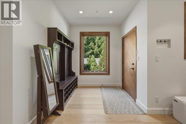 Entryway with light wood floors, a bench, and a large mirror. - 1205 Mount Fee Road, Whistler