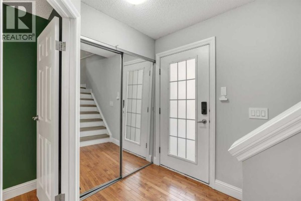 Interior entryway with a staircase, mirrored closet doors, and a glass-paned front door. - 1205 Signal Hill Green Sw, Calgary