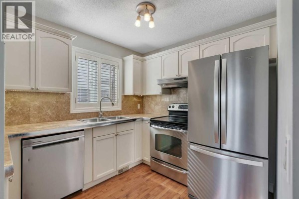 Kitchen with cream cabinets, stainless steel appliances, and granite countertops. - 1205 Signal Hill Green Sw, Calgary