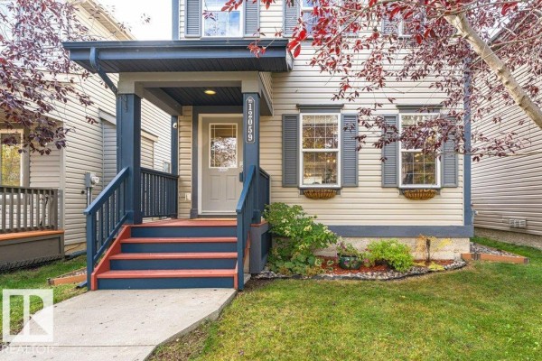 Close-up view of the front entrance, showing a blue porch with red stairs and a gray door. - 12059 19 Av Sw, Edmonton