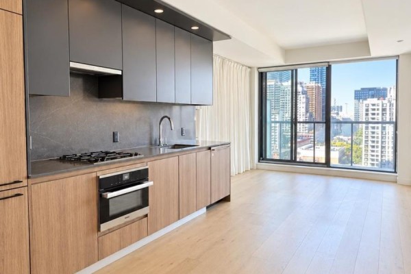 Open concept living area showing kitchen, dining, and sitting space with large windows. - 1206 - 81 Wellesley Street, Toronto